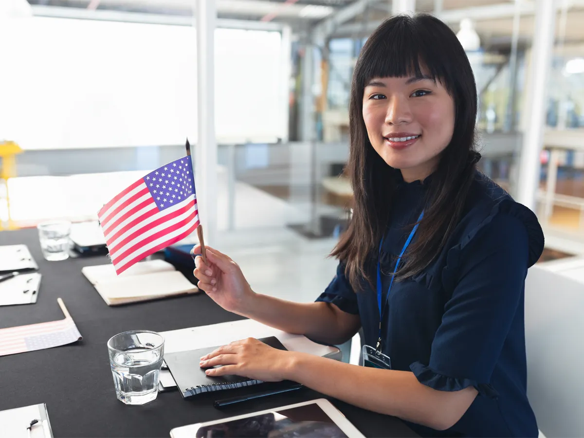 Smiling applicant practicing for US citizenship test with US flag