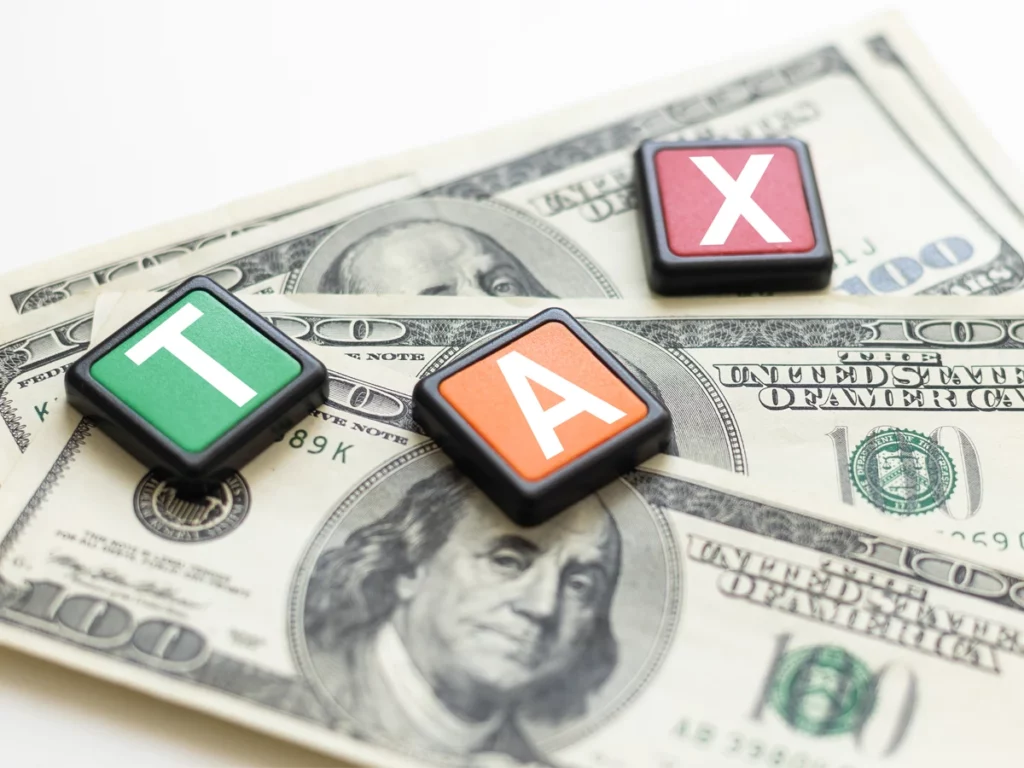 Cubes spelling TAX on top of dollar bills, representing tax responsibility in N-400 citizenship application