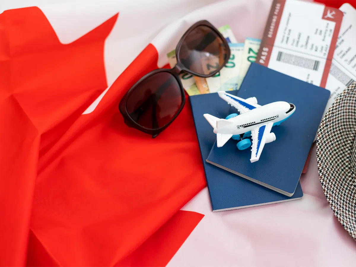Canadian passport with toy airplane and Canada flag representing how to apply for Canadian passport.