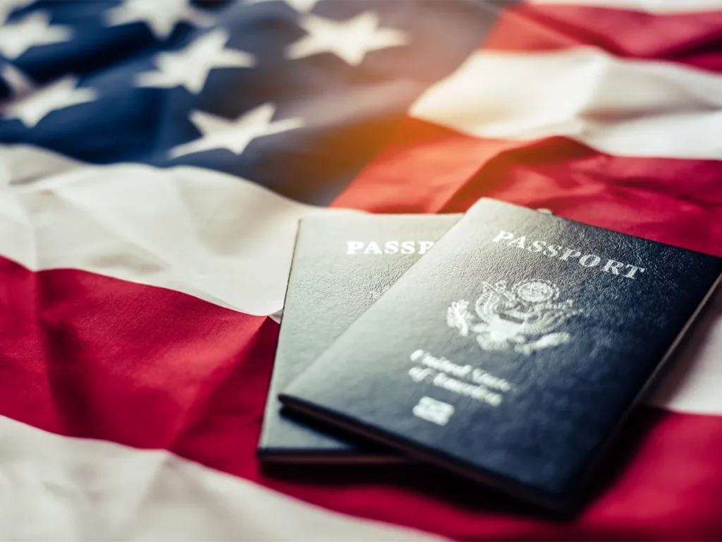 ¿Qué países permiten la doble ciudadanía con Estados Unidos? Pasaportes extranjeros descansando sobre una bandera estadounidense, simbolizando los países que permiten la doble ciudadanía en Estados Unidos.