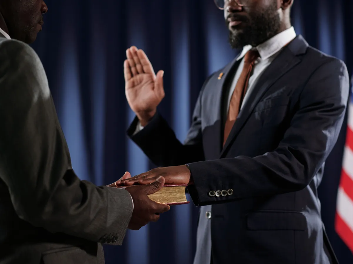 A permanent resident raising their right hand to take the oath of allegiance during a formal citizenship ceremony.
